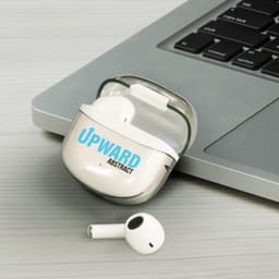 A pair of white Bluetooth earbuds in a charging case, placed next to a laptop on a grey surface.