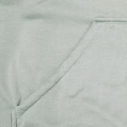 A close-up of a light green fabric featuring a seamless pocket, part of a hoodie design.