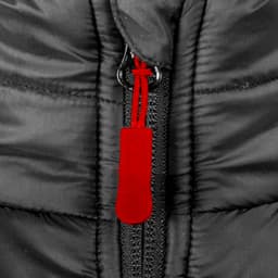 A close-up of a black puffer vest featuring a red zip puller and a central zipper. The material appears insulated.