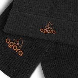 A black scarf and beanie set featuring an orange logo. The beanie has a ribbed texture.