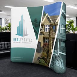A curved stretch media wall featuring green and white sections with a logo and images of houses.