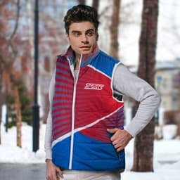 A red and blue custom puffer vest featuring a logo, worn by a model in a winter setting.
