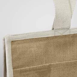 A jute cooler bag in natural brown, featuring a sturdy handle and a simple design, with a small logo on one side.