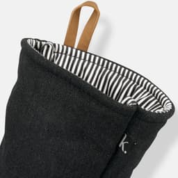 A dark grey oven mitt with a striped interior and a leather loop for hanging. It features a small logo.