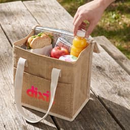 A cooler bag in natural tones containing a sandwich, apple, juice bottle, and a napkin, with an outer logo.