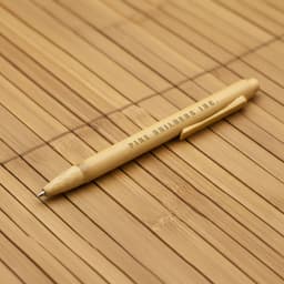 A bamboo pen with a natural finish, featuring a clip and branding. The background is made of bamboo material.