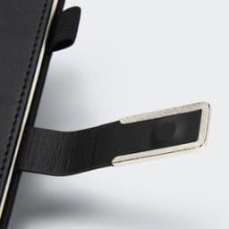 A black diary with a silver metal tab and textured cover, featuring a brand logo.