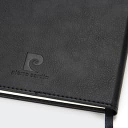 A black diary with a textured cover and a logo embossed on the front. It has a ribbon bookmark.