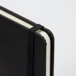 A4 daily diary in black with an elastic band closure and rounded corners. Features a textured cover and plain pages.