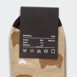 A pair of beige ankle socks featuring a playful animal pattern, with a dark brown heel and toe. Includes a product label.