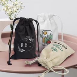Three small cotton gift bags in black, white, and natural colour, featuring various designs and drawstring closures.
